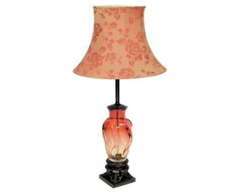 A red to amber spiral moulded glass table lamp, with a metal fitting, and lobed metal circular base, raised on four feet and 