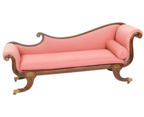 A Regency mahogany chaise lounge, with a scrolling back and headrest, upholstered in overstuffed repeating floral pink fabric