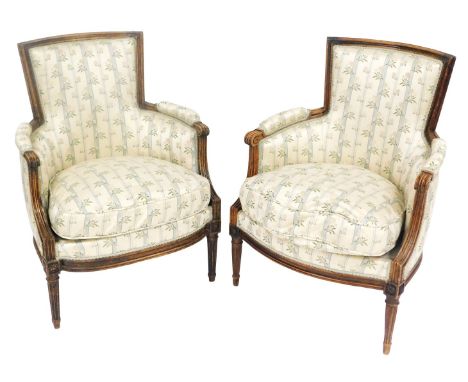 A pair of Victorian mahogany tub armchairs, upholstered and overstuffed cream and pale blue striped and floral fabric, with l