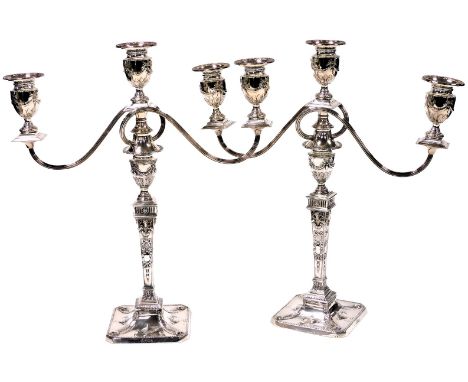 A pair of Victorian Adam style three branch loaded silver candlesticks, the holders embossed with bows, laurel swags and leav