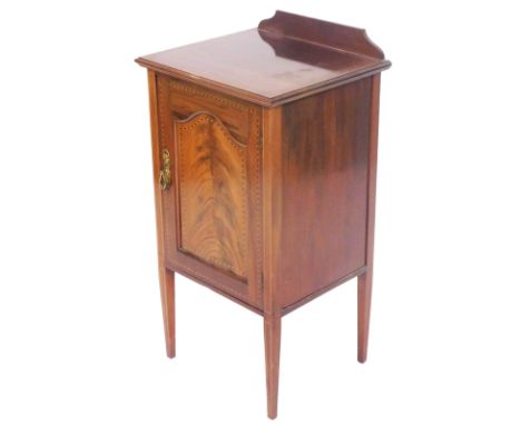 A Edwardian mahogany and cross banded pot cupboard, with a panelled door opening to reveal a single shelf, raised on tapering