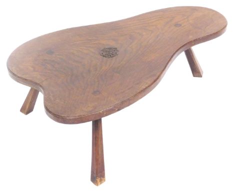 A late 20thC oak coffee table, of abstract form, carved centrally with a rose motif, raised on chamfered outswept supports, 2