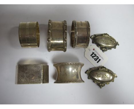 Three Hallmarked Silver Napkin Rings; together with two further napkin rings and two decanter labels "Whiskey" and "Gin" (lac