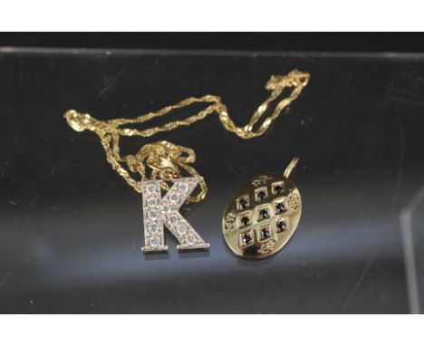 A large 9ct gold 'K' pendant set with white stones on 9ct gold chain together with a large yellow metal oval pendant set with