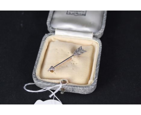 A yellow and white metal diamond encrusted arrow brooch