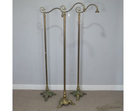 A set of three Victorian brass standard Lamps, having a scrolled single sconce over a central cylindrical column, leading dow