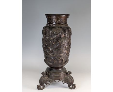 A large Japanese Meiji Period bronze Vase (1868 - 1912), decorated in relief of stylised Peacocks and Flora, raise on scrolle