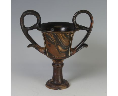 An Apulian pottery red figure Kantharos, raised on a knopped stem with a bell shaped body, each side painted a female head wi