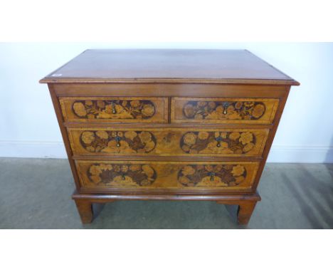 A walnut veneered inlaid chest of two short over two long graduated drawers raised on bracket supports, each drawer with foli