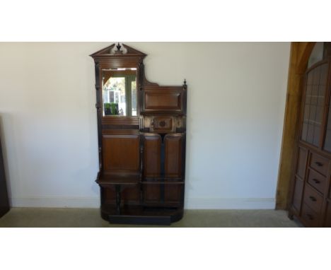 A late Victorian mahogany hall stand bevelled mirror, carved pediment over glove box with door, stick stand below - Height 19