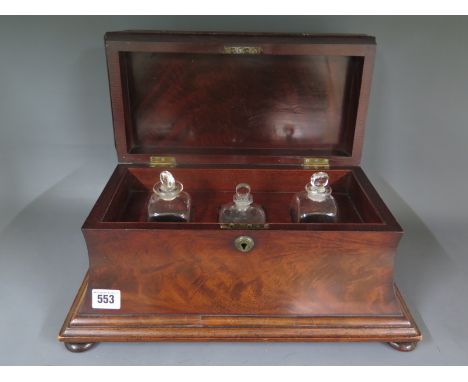 A Regency mahogany tea caddy with a later fitted interior with three antique cologne bottles with stoppers