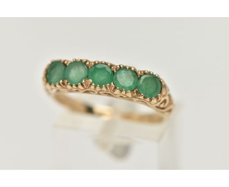 A 9CT GOLD FIVE STONE EMERALD RING, five circular cut emeralds, each claw set, scrolling gallery and shoulders leading onto a