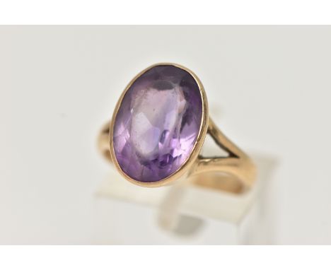 A YELLOW METAL AMETHYST RING, large oval cut amethyst, measuring approximately length 15.2mm x width 11.3mm, bifurcated shoul