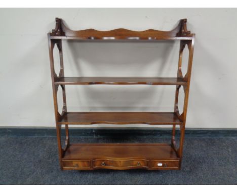 A mahogany four tier wall shelf fitted three drawers beneath 