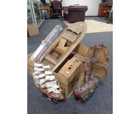 A box containing HMS Endeavour modelling kit in box, two further part built model boats, two model galleons on stands