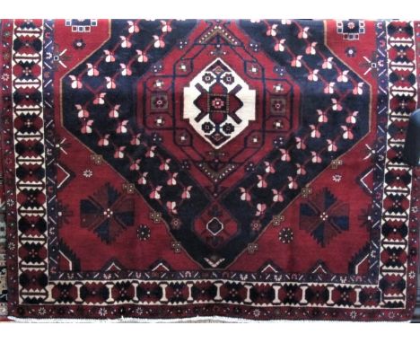 Good quality Bakhtiar carpet, with large central blue and white medallion framed by geometric foliage upon a red ground, 295 