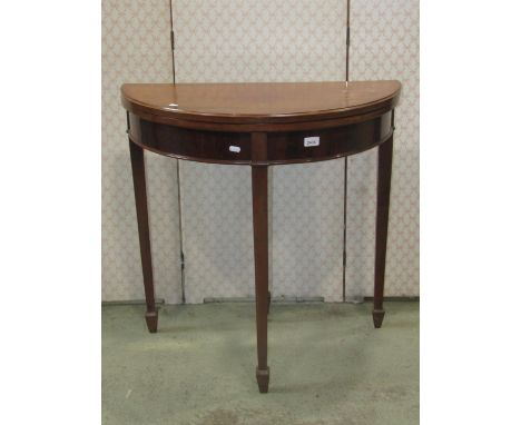 A Georgian style mahogany demi-lune foldover top card table, with baise lined interior raised on four square tapered legs and