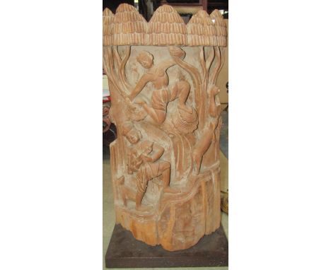 A carved Indian hardwood panel cut from half a tree trunk, deep relief detail showing characters amongst foliage, 95 cm in he