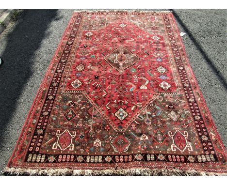 Good quality full pile Qashgai carpet with intricate stylised still life decoration around a central medallion upon a washed 