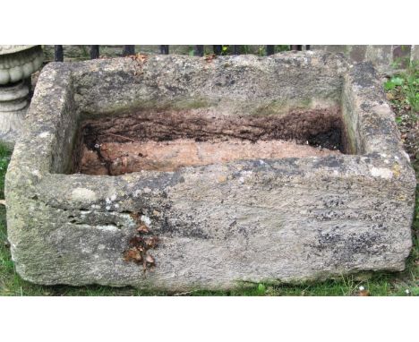 A weathered natural stone trough of rectangular form, thick walled, with cut out corner channel, 96cm long x 70cm wide x 33cm