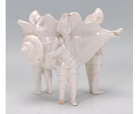 A 19th Century Continental pearlware ceramic table salt in the form of a conch shell supported by three flemish figures. Meas