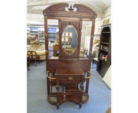 A late Victorian mahogany hall stand with central, oval mirror, brass coat hooks and central glove drawer, supported on turne