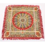 AN ISLAMIC WOOL TABLE CARPET with a central radiating design within borders decorated with