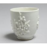 AN 18TH CENTURY BOW BLANC DE CHINE COFFEE CUP decorated with applied prunus sprigs.