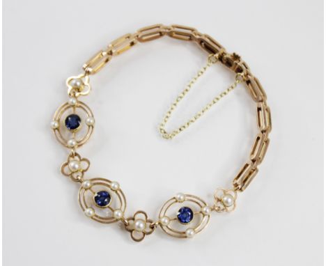 An Edwardian sapphire and cultured pearl set bracelet, comprising three pierced oval panels each set with a mixed cut blue sa