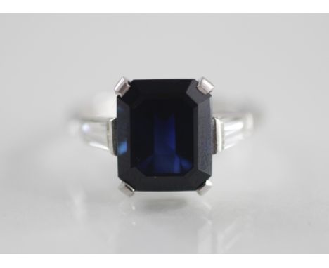 An Art Deco sapphire and diamond ring, the central rectangular step cut (untested) sapphire measuring 11mm x 8mm, claw set in