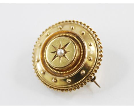 A Victorian pearl set Etruscan style target brooch, comprising a central pearl gypsy to a yellow metal tiered circular surrou