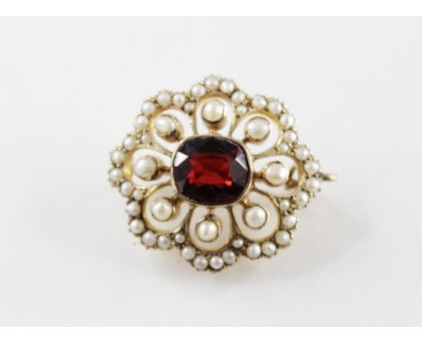 An Edwardian garnet and seed pearl floral cluster brooch, the central cushion cut garnet measuring approx. 8mm x 6mm, bezel s