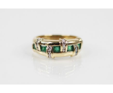 An emerald and diamond set 14ct gold ring, the woven design ring comprising brilliant cut diamond set panels interspersed by 