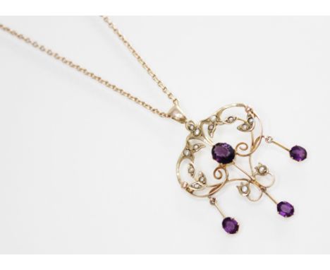 An Edwardian paste and seed pearl set pendant, the openwork scrolling pendant set with amethyst coloured pastes and seed pear
