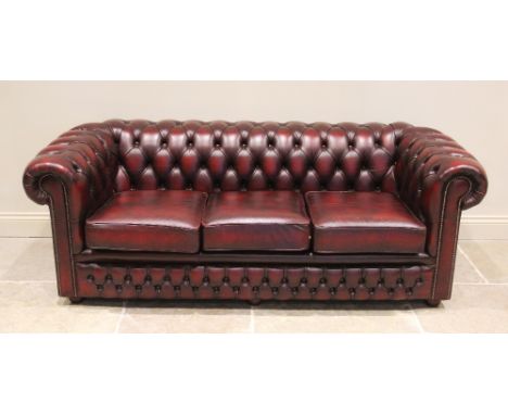 An oxblood red leather Chesterfield settee, late 20th/early 21st century, of typical deep set button back form, with three fi