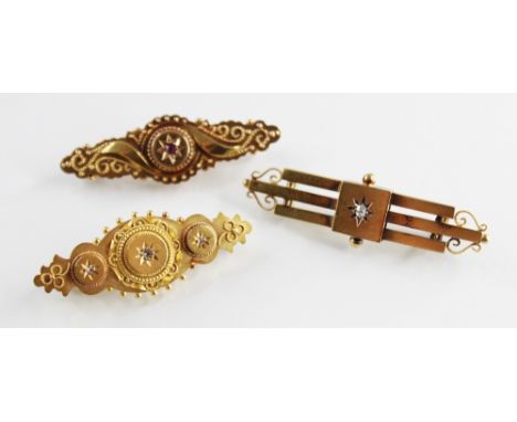An Edwardian Etruscan style 15ct gold bar brooch, the navette shaped brooch set with a mixed cut ruby and applied and beaded 