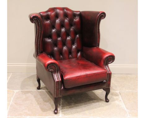 A George II style oxblood red leather wing back fireside armchair, late 20th/early 21st century, the curved win backs enclosi