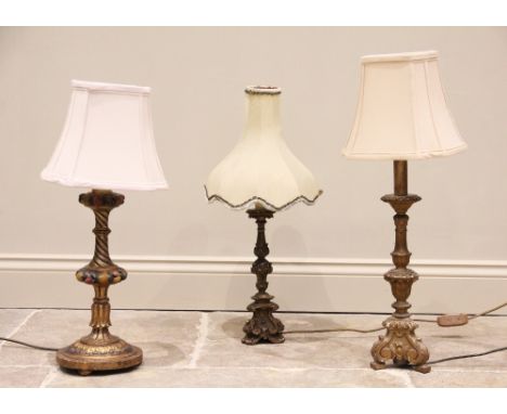 Three gilt wood Rococo style table lamps, 20th century, two of triform with moulded scrolling foliate detail, and the third w