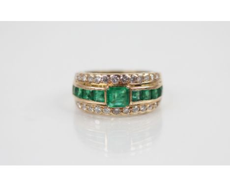 An emerald and diamond ring, the central octagonal step cut emerald measuring 5.25mm x 4.85mm, flanked by four tapering bague