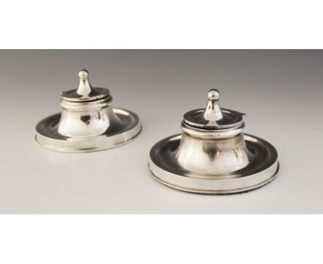 A near pair of Edwardian silver mounted capstan inkwells, William Neale, Birmingham 1907, each with weighted circular bases, 