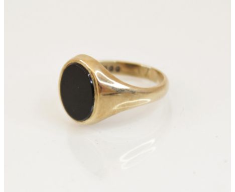 A 9ct gold black onyx signet ring, the oval onyx panel measuring 12mm x 10mm, set in 9ct yellow gold to tapering shoulders an