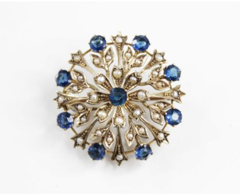 An Edwardian blue stone and seed pearl set circular brooch/pendant, the circular floral design frame set with nine green-blue