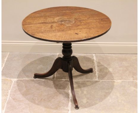 A George III oak tripod table, the circular plank top raised upon a ring turned baluster column, extending to three down swep