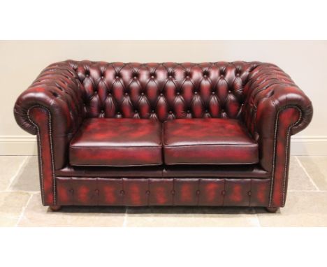 An oxblood red leather Chesterfield settee, late 20th/early 21st century, of typical deep set button back form, with two fitt