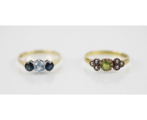 A peridot and seed pearl set 18ct gold ring, comprising a round mixed cut central peridot, flanked by trefoil shoulders set w