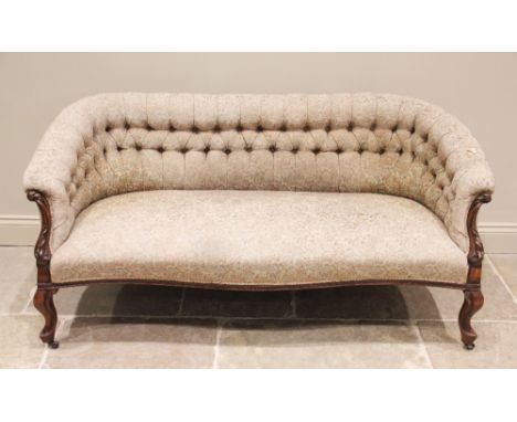 A Victorian walnut framed tub shaped settee, the padded button back extending to carved leaf swept supports, enclosing the se