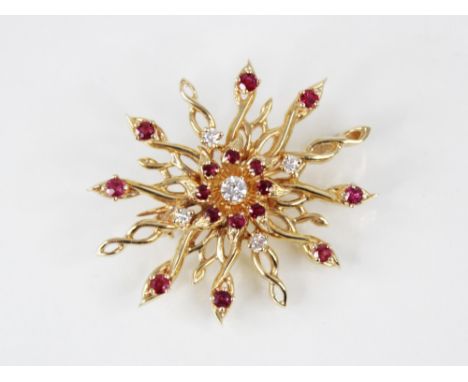 A diamond and ruby set 14ct gold brooch pendant, the twisted sunburst design frame set with brilliant cut diamonds and mixed 