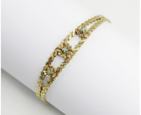 A 9ct gold turquoise set bracelet, comprising three yellow metal flowers set with turquoise colour cabochons, set to a two ro