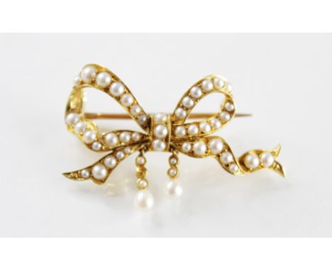 An early 20th century pearl set bow brooch, the unmarked yellow metal bow form brooch set with graduated half pearls, suspend