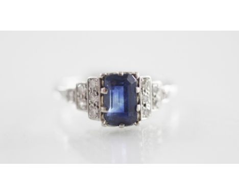 An Art Deco diamond and sapphire ring, the rectangular step cut sapphire measuring 7mm x 4mm, claw set to tapering shoulders 